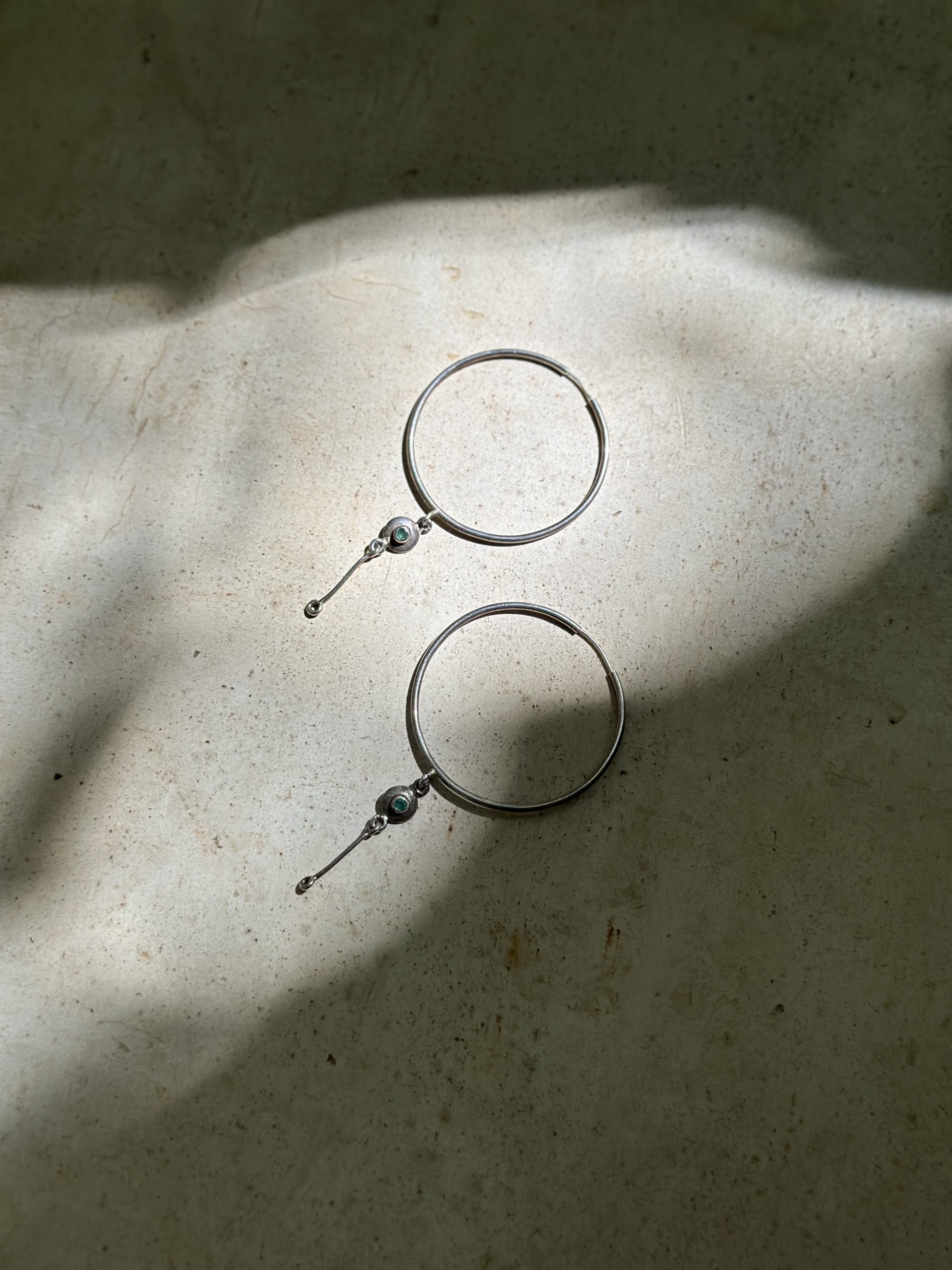 Mukani hoop earrings against skin in natural light.