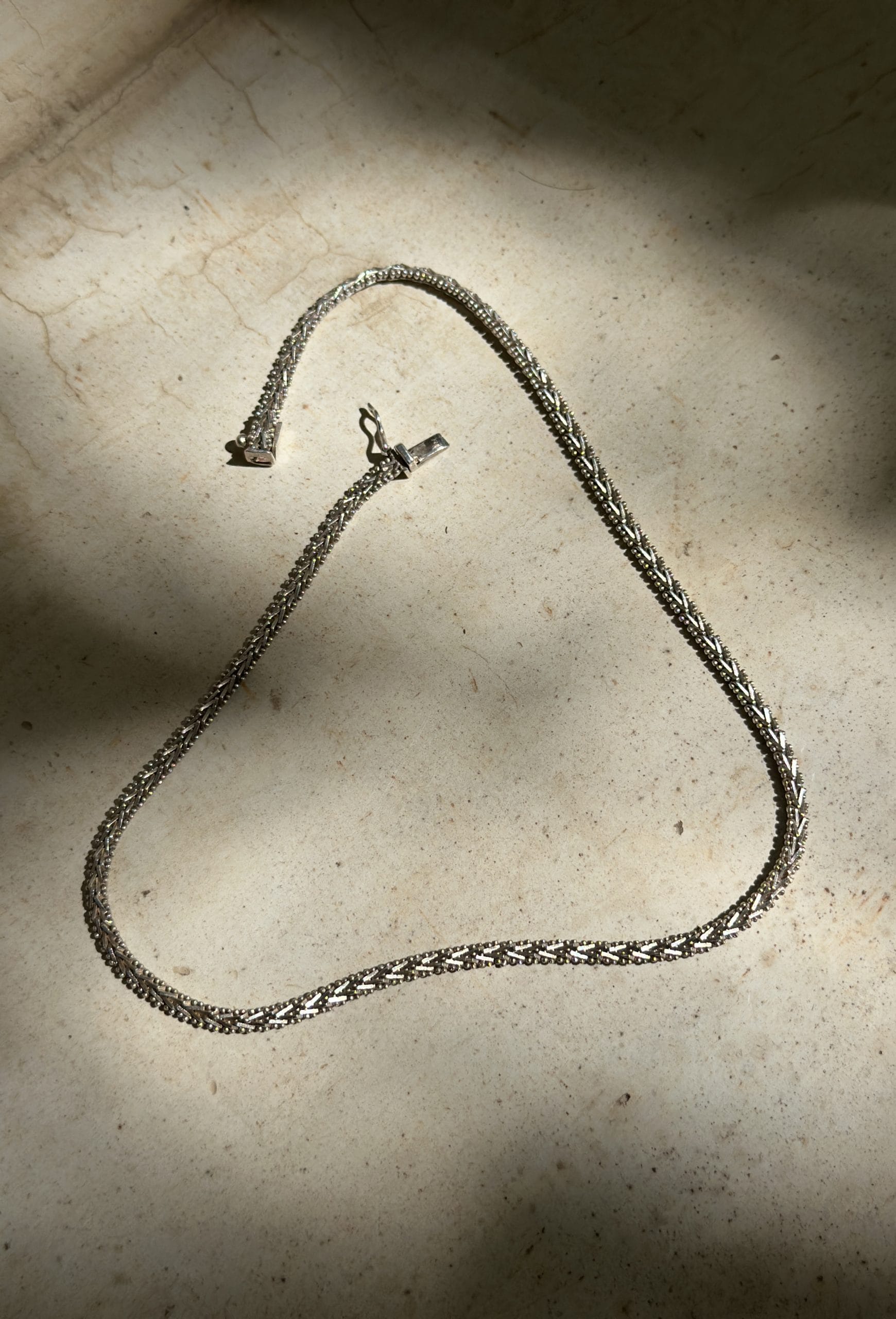 Mukani necklace among leaf shadows.
