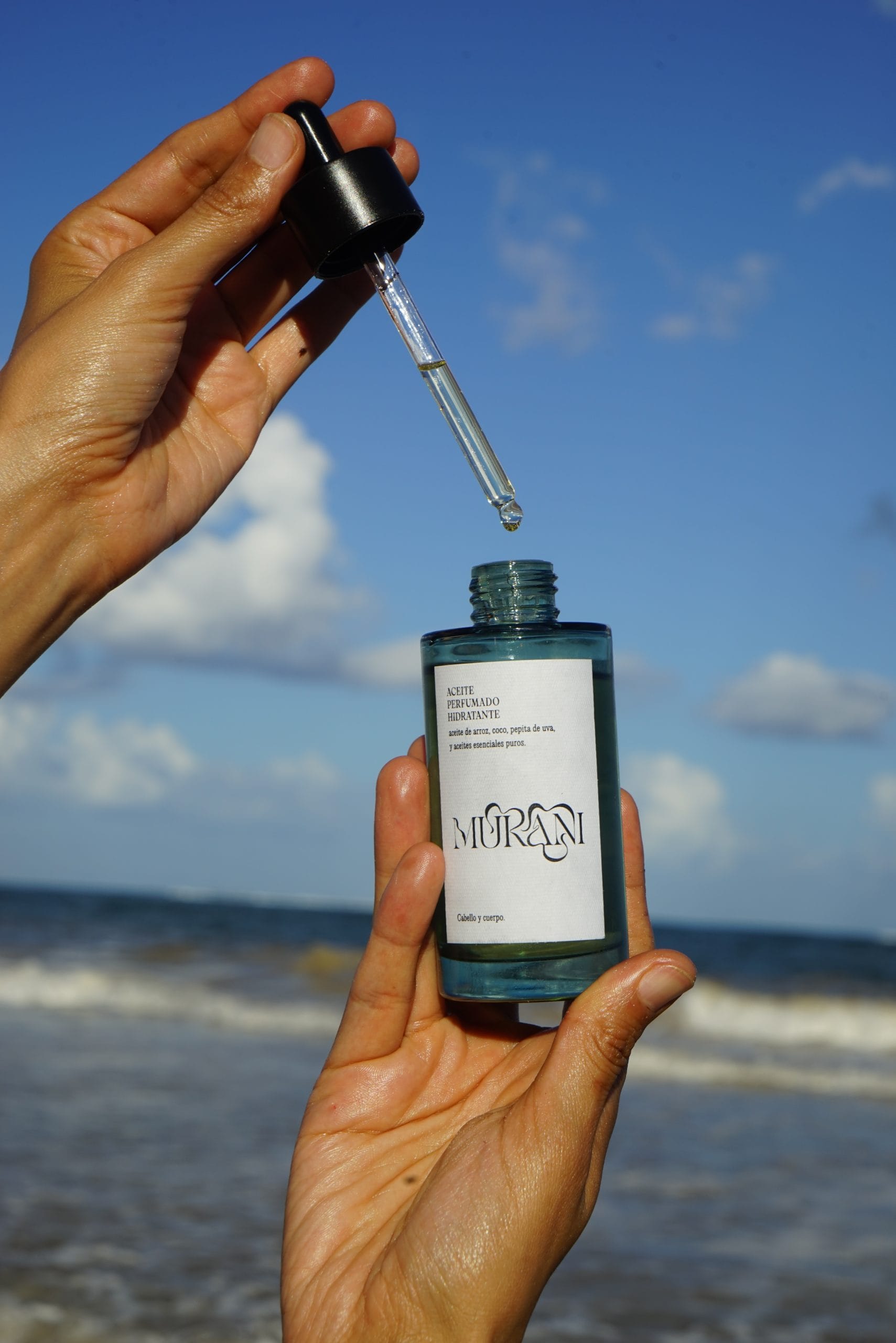Mukani botanical oil held against the sky.